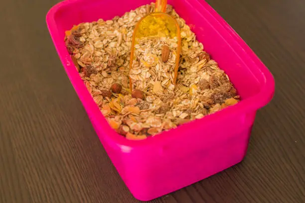 Pink container with oatmeal and nuts, close-up