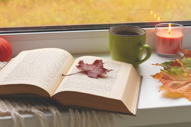 istock autumn still life. books, leaves, cup and candlestick on window. 1053900344