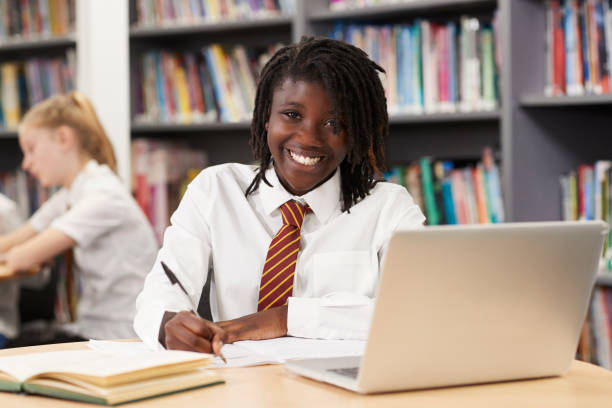 retrato de mujer high school secundaria estudiante usando uniforme trabajando en ordenador portátil en la biblioteca - uniforme fotografías e imágenes de stock