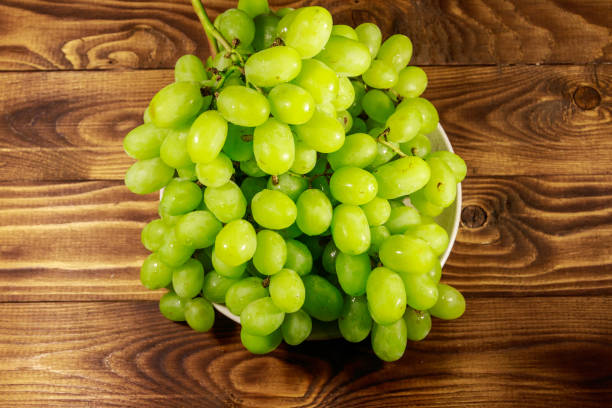 istock Tasty fresh white grape in a plate on wooden table 1053901398