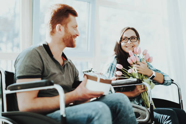 istock Man Disabled with Gift Box and Woman with Flowers. 1053909316