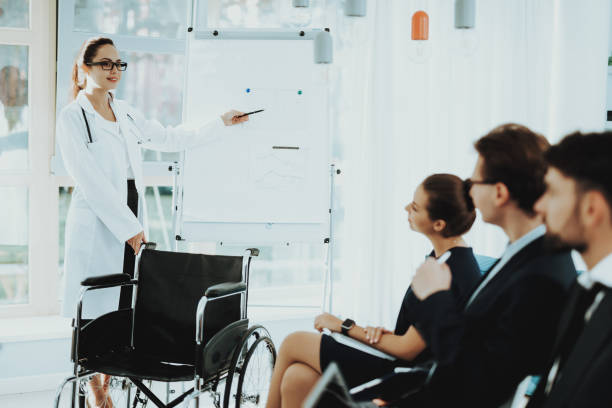 istock Woman in White Coat Shows Pointer to White Board. 1053909394