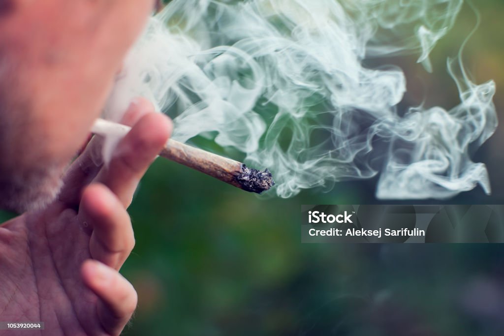 A man smokes a joint. Medical marijuana use and legalization of the cannabis, light drugs concept Man smokes a joint. Medical marijuana use and legalization of the cannabis, light drugs concept Hashish Stock Photo