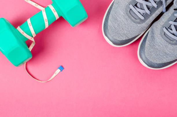 istock Green dumbbell and sneakers on pink background 1053926198