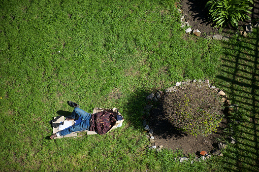 141 Castel Road, Shelter, Cape Town, South Africa - 23 August, 2018 : High angle view down on the grass of the homeless shelter with a man sleeping safely on the grass surrounded by a fence.