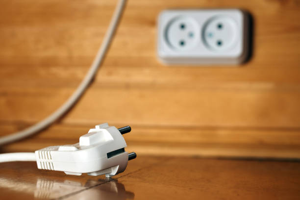 istock White electric plug lying on a floor with a socket on the wooden wall on the background 1053933792