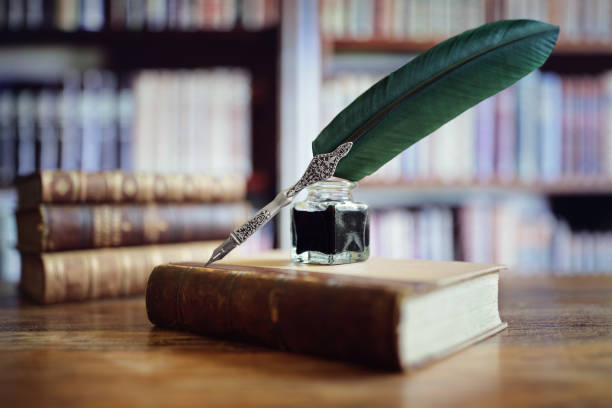 pluma en un viejo libro en una biblioteca - ink bottle fotografías e imágenes de stock