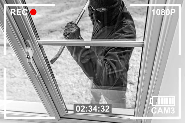 CCTV view of burglar breaking in to home through window CCTV view of burglar breaking in to home through window with crowbar stealing crime stock pictures, royalty-free photos & images