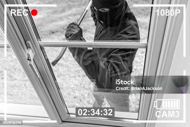 Cctv View Of Burglar Breaking In To Home Through Window Stock Photo - Download Image Now