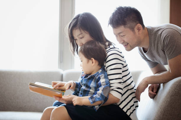 istock Mother and son reading a book together and father watching it 1053936488