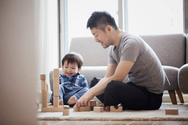 padre e figlio giocano insieme con gli elementi costitutivi - block togetherness happiness indoors foto e immagini stock