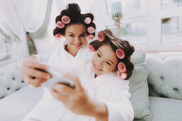 istock Smiling Mom with Daughter doing Selfie in Salon. 1053938134