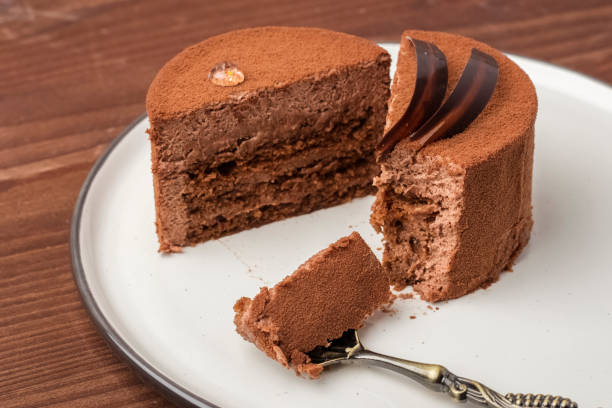 istock Chopped in half Chocolate cake in a light plate with a dessert spoon on a wooden table 1053940256