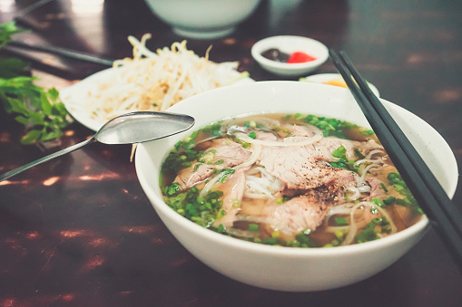 Pho Bo - Vietnamese fresh rice noodle soup with beef, herbs and chili. Vietnam's national dish.