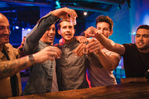 Group of Men Toasting Their Drinks Group of men on a night out toasting their shots before drinking them all in one go. They're celebrating the new year of 2019. tequila shot stock pictures, royalty-free photos & images