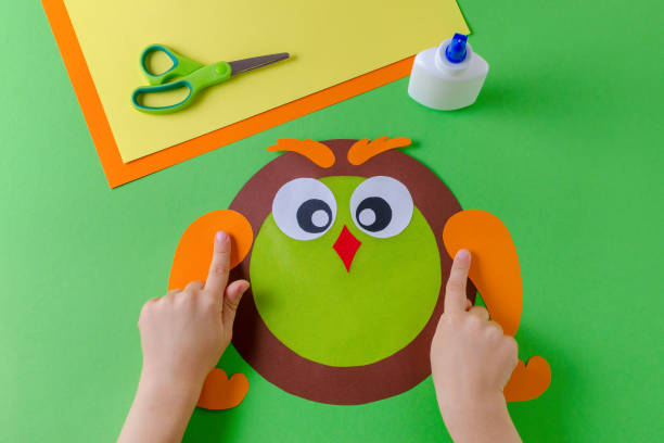 istock kid is making a owl with color paper, glue and scissors 1053949464
