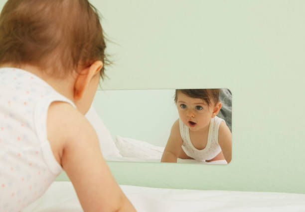 鏡を見て赤ちゃん - simplicity innocence new life clothing ストックフォトと画像