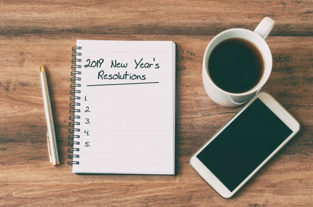 2019 New Year's Resolutions text on notepad New year Concept - 2019 New Year's Resolutions text on notepad. Smartphone, pen and cup of copy background. 2019 new year resolution stock pictures, royalty-free photos & images