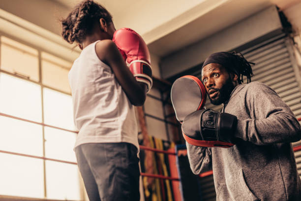 istock Low angle view of a boxing girl training with her coach 1053955558