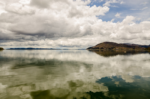 Lake Titicaca like a mirror reflecting the clouds with a mountain