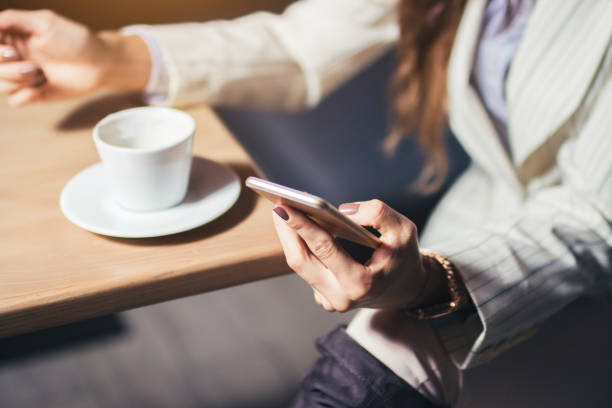 istock Modern girl sitting at the table drinking coffee and using a mobile phone. 1053958860