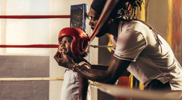 istock Kid wearing boxing head guard standing inside a boxing ring 1053960446