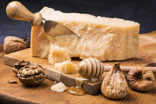 wooden chopping board on which is disposed the ripened cheese, dried figs, walnuts and honey