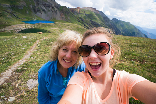 Mother and teenage daughter take a selfie picture from a high vantage point above Ice Lake in the Ice Lakes upper basin, 12,600 ft, Silverton, Colorado, USA