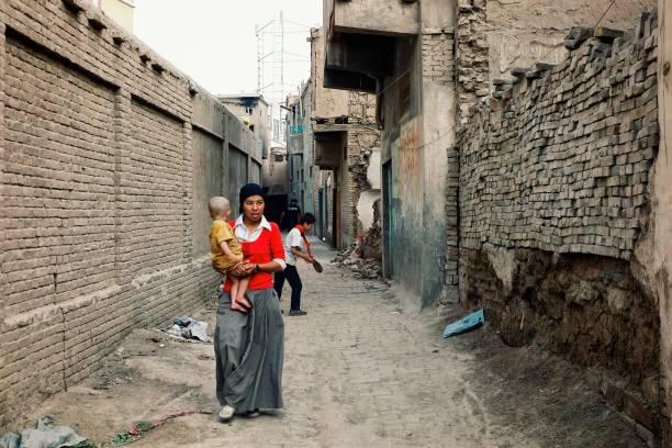 молод�ая мать уйгуров с ребенком в традиционной старой части города - uighur стоковые фото и изображения