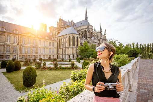Young woman enjoying beautiful view on the Reims cathedral and gardens traveling in Reims city, France. Woman is out of focus