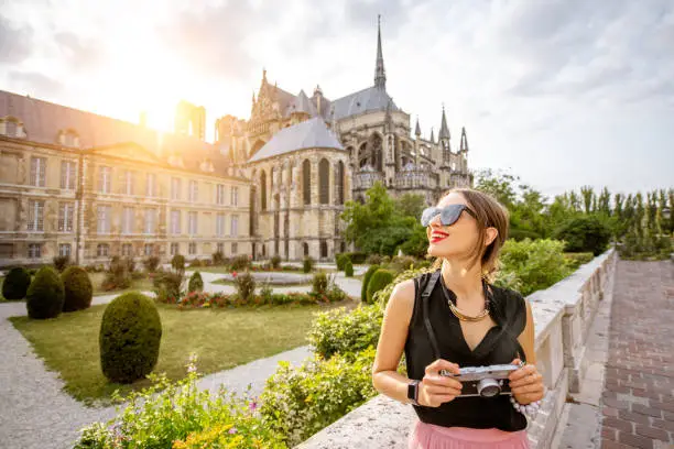 Young woman enjoying beautiful view on the Reims cathedral and gardens traveling in Reims city, France. Woman is out of focus