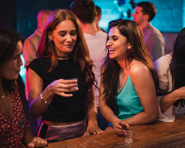 Women Laughing at Her friends Taking Shots Friend laughing at her friends in the nightclub drinking their shot, They're both pulling funny faces. tequila drink stock pictures, royalty-free photos & images