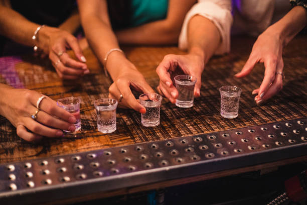 female hands about to pick up shot glass - shot glass glass alcohol color image imagens e fotografias de stock