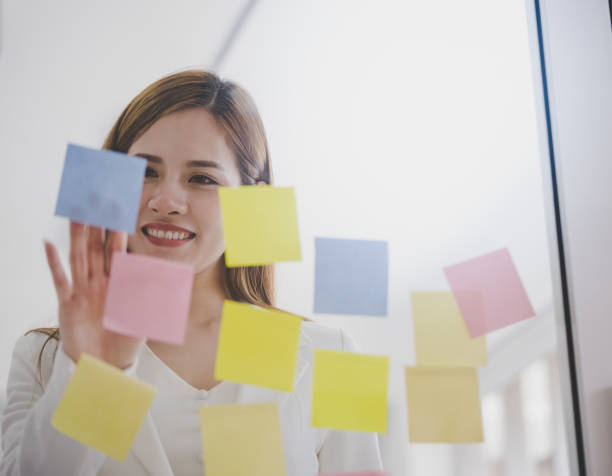 istock Business woman is writing idea on to post it windows for plan 1053974112
