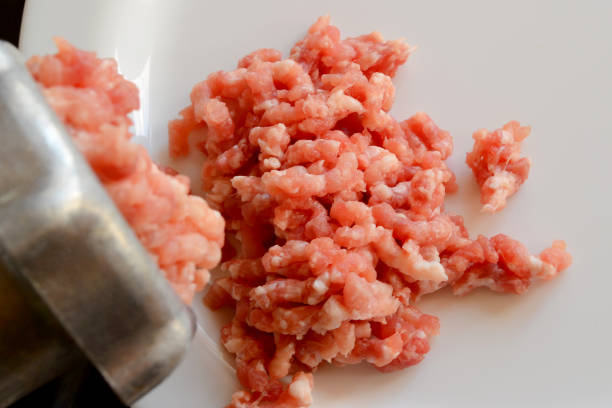 istock Making minced meat with a meat grinder and red raw mince on a white plate, top view 1053979446