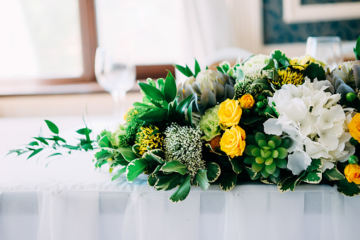 Elegant bride and groom table setting for the wedding with candlestick centerpiece in yellow and green colors