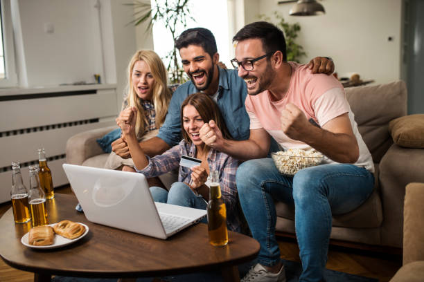 istock Friends cheering for their team and betting online 1053987536