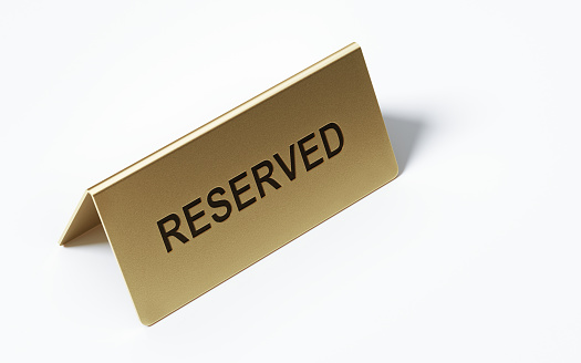 Brass reserved sign standing on white background. Horizontal composition with copy space. High angle view. Clipping path is included.