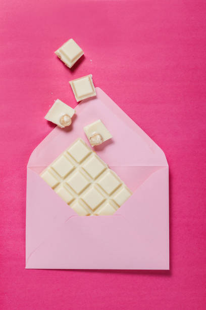 istock White chocolate in a pink envelope on a pink background. 1053989898