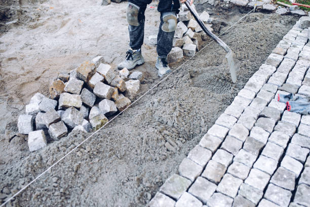 istock construction worker placing stone tiles for pavement, terrace. Worker placing granite cobblestone pavement at terrace 1053990210