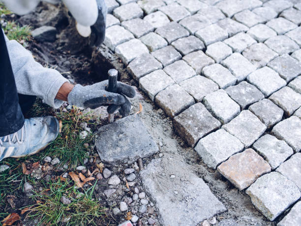 istock construction worker placing stone tiles for pavement, terrace. Worker placing granite cobblestone pavement at terrace 1053990354