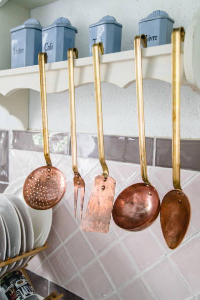 istock Copper kitchen utensils, spoons and spatulas hanging next to pink tiles 1054000920