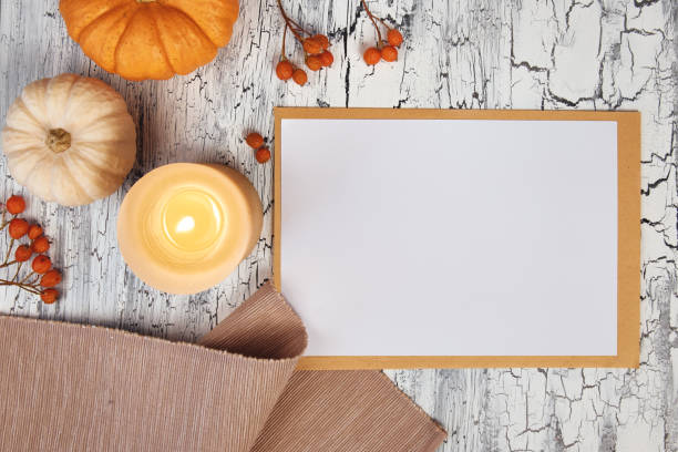 istock Autumn decorations: pumpkins, napkin and berries on rustic table, and a white block note, top view, space 1054009278