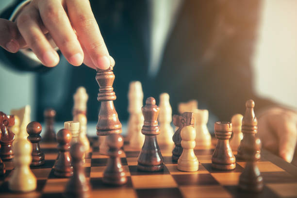istock Business man moving chess figure with team behind - strategy or leadership concept 1054009746