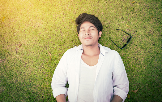 Man lying on green grass with happy