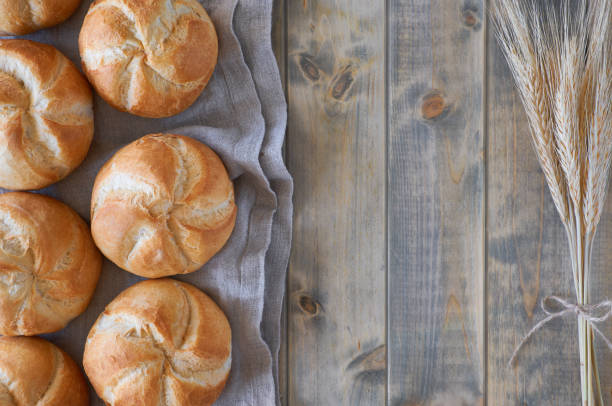 istock Crusty round bread rolls, known as Kaiser or Vienna rolls on linen towel on rustic wood 1054019574