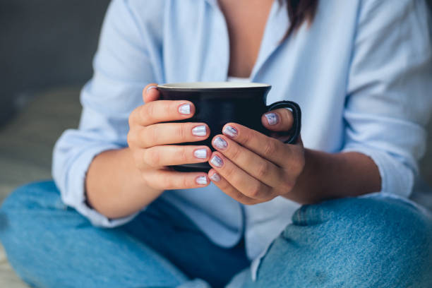 istock Cute girl with a beautiful manicure drinking coffee 1054032280