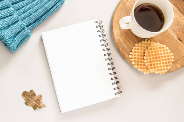 Two waffles, a cup of coffee, blue hat, leaf, and note on grey background.