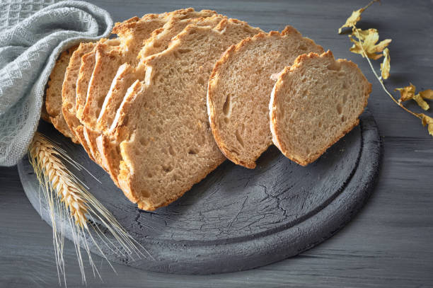 istock Slliced white round bread with wheat ears on gray rustic wood 1054061500