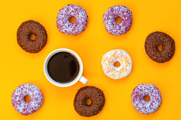 istock Delicious glazed donuts and cup of coffee on yellow surface 1054068268